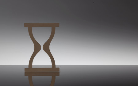 Closeup of model wooden hourglass on black background, copy space