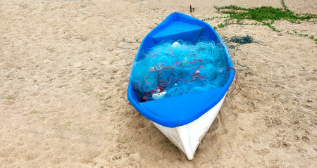 small fishing boat on the shore of beach covered with fishing netの写真素材