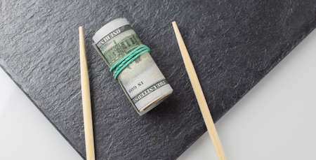 roll of dollars on a black plate on the white background