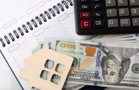 Small wooden model house on the background of US dollar bills on the planningの写真素材