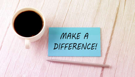 MAKE A DIFFERENCE text on blue sticker with cofee and pen