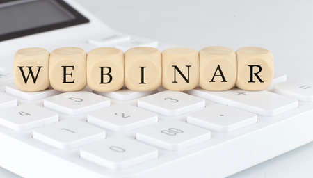 Wooden cubes with text WEBINAR on the calculator, business