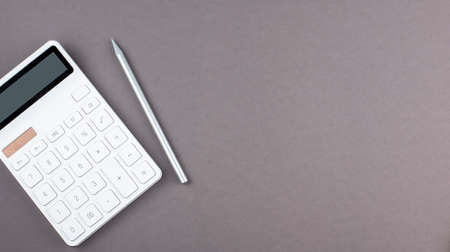 Overhead view of work desk with calculator and pen on the gray background, copy spaceの写真素材