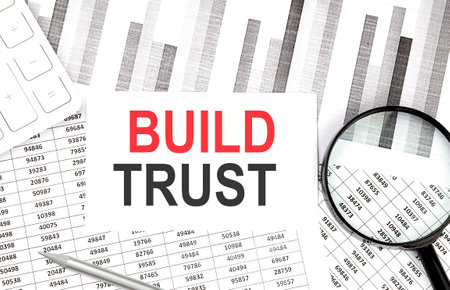 BUILD TRUST text on paper with calculator, magnifier, pen on graph backgroundの写真素材