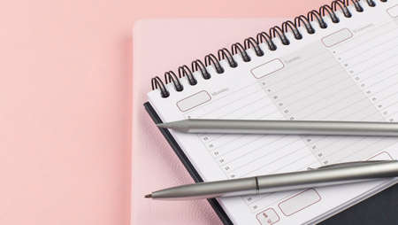 Planner with pen and pencil on pink backgroundの写真素材