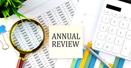 ANNUAL REVIEW text on sticker on diagram with magnifier and calculator. Businessの写真素材