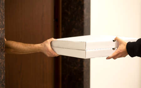 Concept delivery.Young handsome man delivering pizza on the door