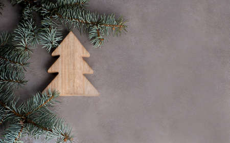 Spruce branch with wooden christmas tree on gray background, copy spaceの写真素材