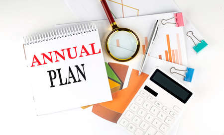 White notepad text ANNUAL PLAN with diagram, chart, calculator on white background