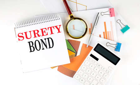 White notepad text SURETY BOND with diagram, chart, calculator on white backgroundの写真素材