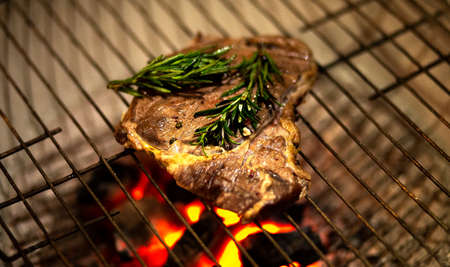 Beef steak on grill with smoke and flamesの写真素材