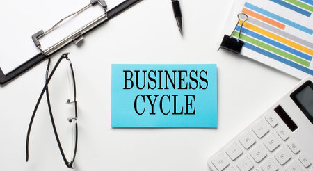 Stickers with chart,calculator and paper with text BUSINESS CYCLE on white backgroundの写真素材