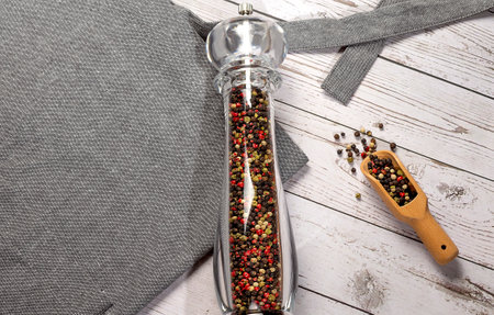 Culinary background, kitchen apron and pepper mill on wooden background