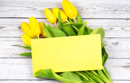 Top view photo yellow tulips and envelope on the wooden background, copy spceの写真素材