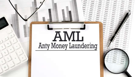 Anti-money laundering AML text on a clipboard on light background with charts paperの写真素材