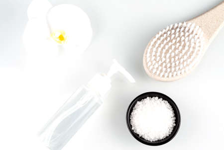 Bath and spa accessories on a white background. Brush for dry massage and sea salt with orchid branch.の写真素材
