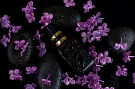 Glass dropper bottle with black stones and lilac. topview. skincare cosmetic. beauty conceptの写真素材