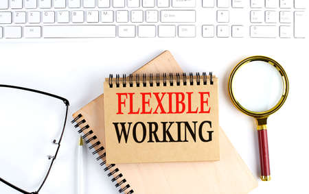 FLEXIBLE WORKING text in office notebook with keyboard, magnifier and glasses , business conceptの写真素材