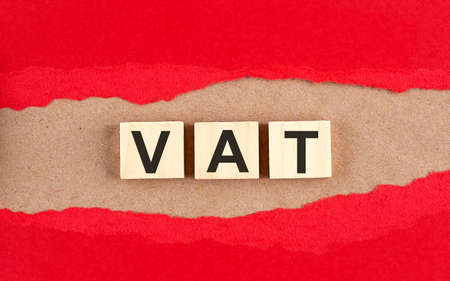 Vat word on wooden cubes on a red torn paper , financial concept backgroundの写真素材