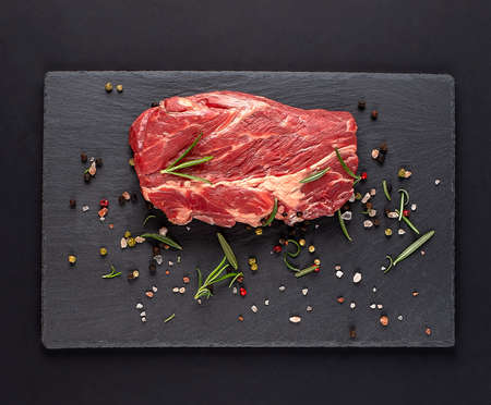 Raw marbled beef steaks with spices on a black cutting board on a black background. top view withの写真素材