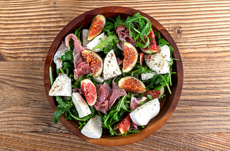 Salad with arugula , figs, prosciutto and mozzarella on a wooden backgroundの写真素材