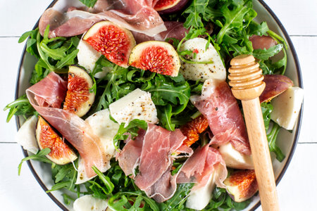 Salad with arugula , figs, prosciutto and mozzarella on a white wooden backgroundの写真素材