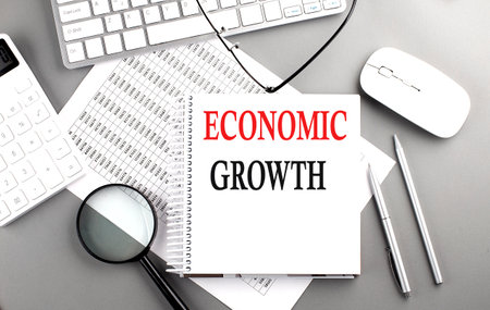 ECONOMIC GROWTH text on a notepad on chart with keyboard and calculator on gray background