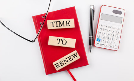 TIME TO RENEW text on the wooden block on red notebookの写真素材