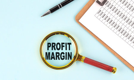 PROFIT MARGIN text on a magnifier with clpboard on blue background