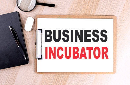 BUSINESS INCUBATOR text on a clipboard on wooden backgroundの写真素材