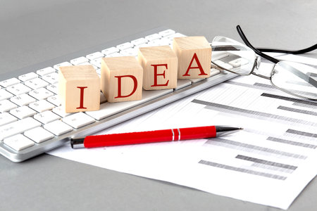 IDEA written on wooden cube on the keyboard with chart on gray backgroundの写真素材