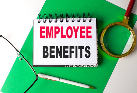 EMPLOYEE BENEFITS text on a notebook on green paperの写真素材