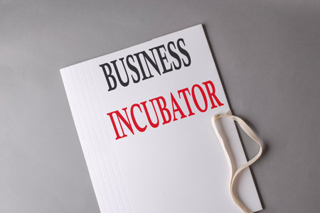 BUSINESS INCUBATOR text on a white folder on gray backgroundの写真素材