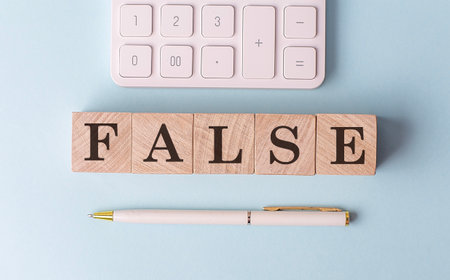 FALSE on a wooden cubes with pen and calculator, financial conceptの写真素材