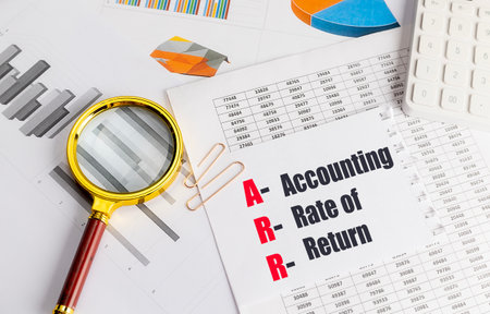 Paper with acronym ARR and its meaning accounting rate of return, magnifying glass, charts, and...