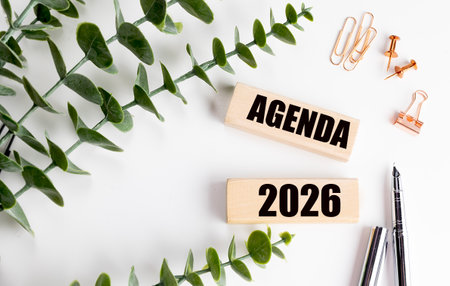 Agenda 2026 text on a wooden blocks with green leaves, paper clips and pen on white office desk background.の写真素材