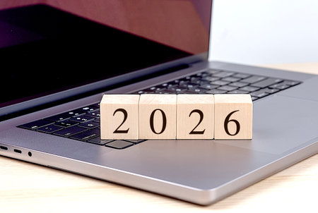 Wooden blocks with number 2026 on a laptop keyboard symbolizing future technology and digital innovation.の写真素材