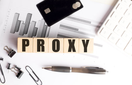 Proxy word on wooden blocks with a charts, credit card, pen, clips and calculator on white office...