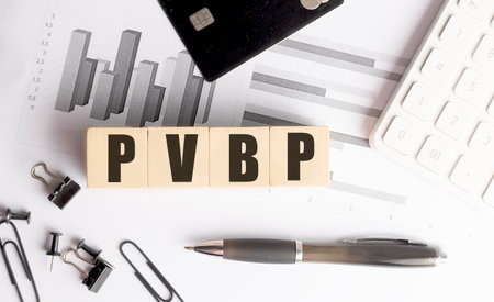 Wooden blocks with a PVBP abbreviation on desk with financial charts, pen, credit card and...