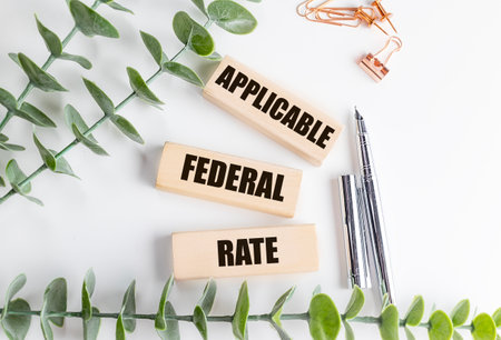 Wooden blocks with a words applicable federal rate on white desk with pens, paper clips and green...