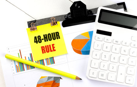 Sticky note with 48-hour rule text on clipboard with a calculator, charts and yellow pencil.