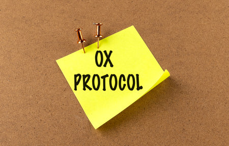 Yellow sticky note with a words 0x protocol pinned to cork board background with copper push pins.の写真素材