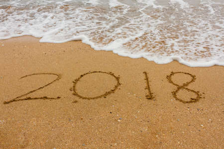 Wave washes inscription 2018 on seashore. New Year 2018の写真素材