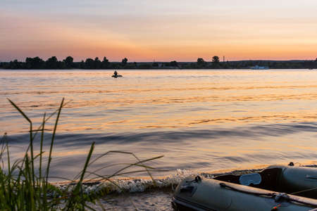 Beautiful sunset on Dnipro river and fishing boat on foregroundの写真素材