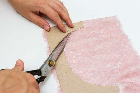 Women's hands cut out lace underwear on a table. Close-up