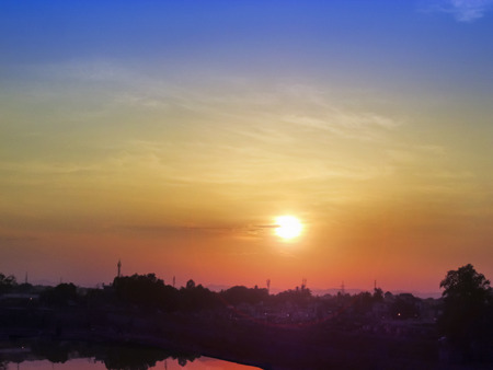 Sunset sky of multiple colors over the city scaterred ray of Sunlight and its reflection on water.の写真素材