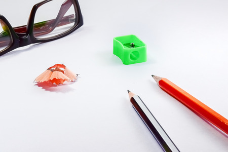 Back to school concept- a Pencil,erasor, sharpner an cut slice of the pencil on white table with or without spectacles not properly aranged isolated.の写真素材