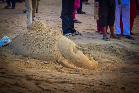 Side face of Lord Buddha head statue facing upward to the sky in the form of sand art made with sand and water hand made by some creative artist on the beach sand of Puri, Odisha, India in winter on 11th February 2020.の写真素材