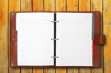 Old brown leather cover notebook on wooden backgroundの写真素材