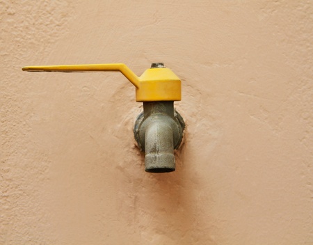 Yellow handle water tap on rough pink wall の写真素材